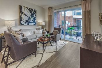 A living room with a grey couch, a brown armchair, and a coffee table at Crabtree Lakeside Apartments, Raleigh, 27612